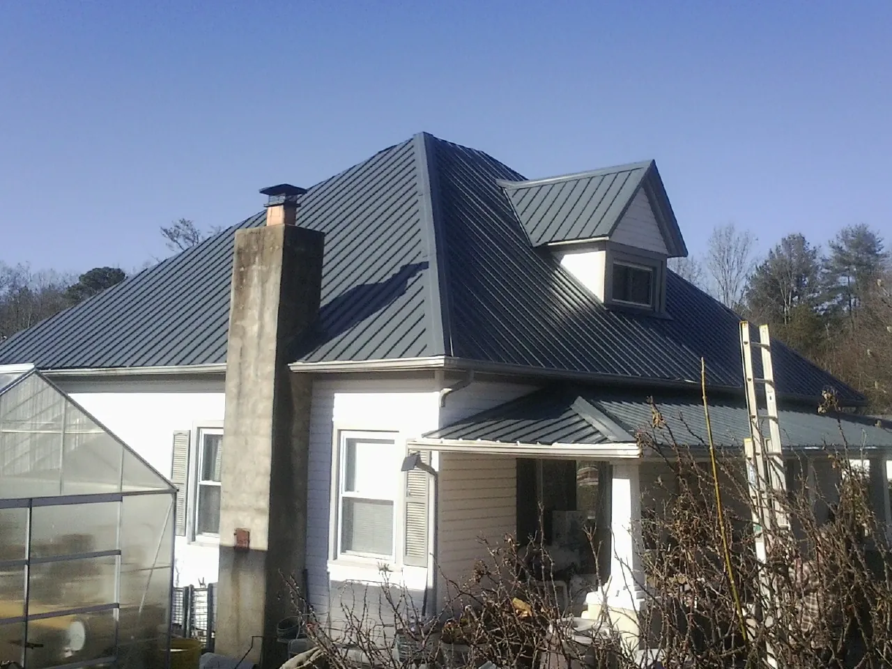 Dark blue standing seam metal roof on a white farmhouse with dormer — Slate & Tile Roof Repair by Roofing Brothers in Woods Cross