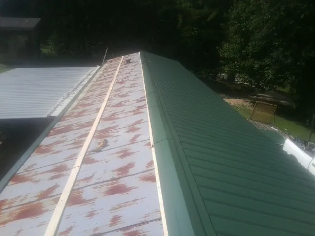Old rusted panels beside newly installed green metal roofing — Wind Damage Roof Repair by Roofing Brothers in Woods Cross