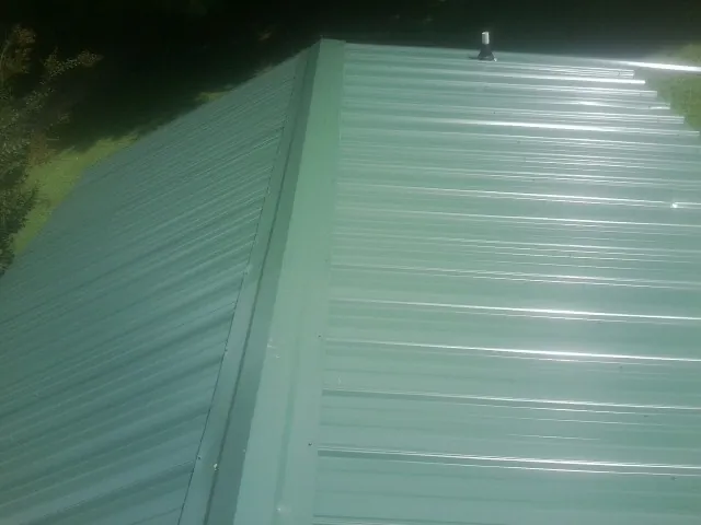 New green metal panels meeting at the ridge of a roof — Flat Roof Repair work by our crew in Woods Cross