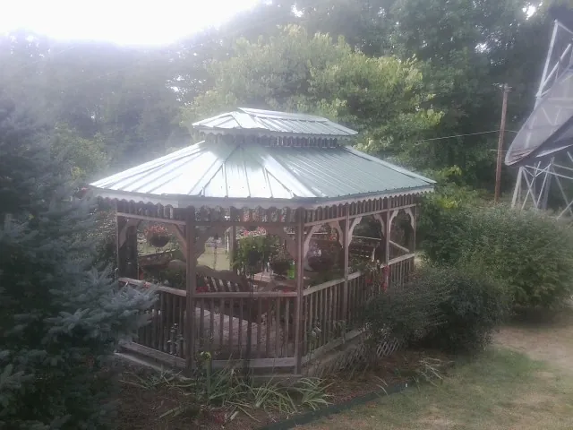 Green metal roof on a backyard gazebo surrounded by garden beds in Woods Cross