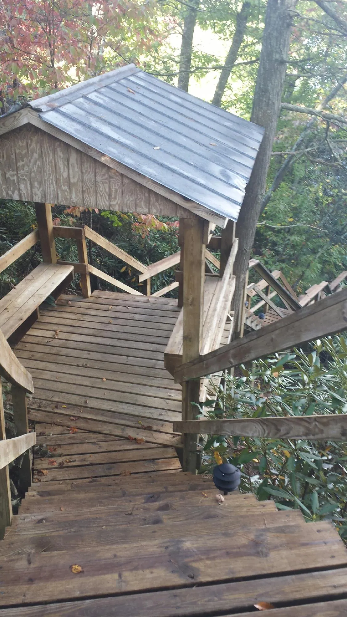 Metal roofed shelter over wooden steps on a wooded walkway — Skylight Repair & Installation work by our crew in Woods Cross