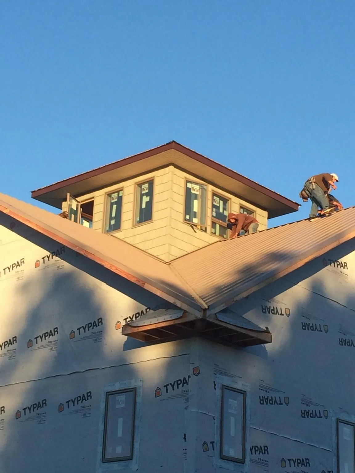 Roofers working around a rooftop cupola on a new metal roof at sunset — Roof Waterproofing in Woods Cross by Roofing Brothers